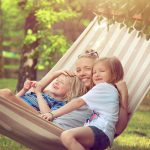 mother + daughters smiling in hammock